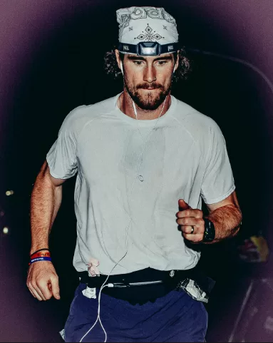 A runner in a head torch and bandana running through the night