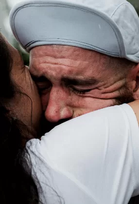 A runner in tears, held close in an embrace